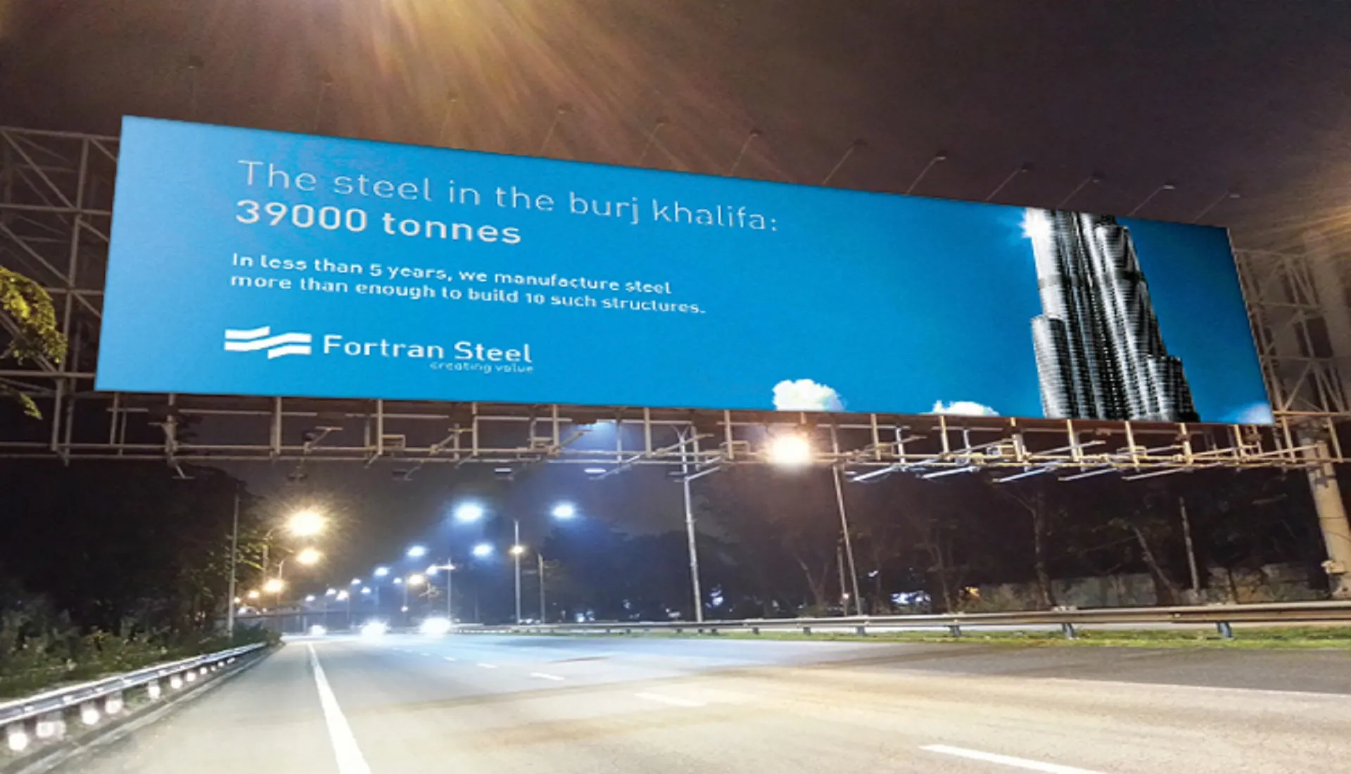Night highway gantry billboard with the Fortran Steel ad “The steel in the Burj Khalifa: 39,000 tonnes” and a photo of the Burj Khalifa.
