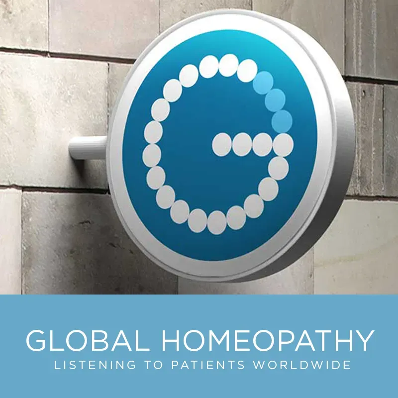 Circular blue lightbox sign with a dotted G logomark on a stone clinic wall, above the line “Listening to patients worldwide”.